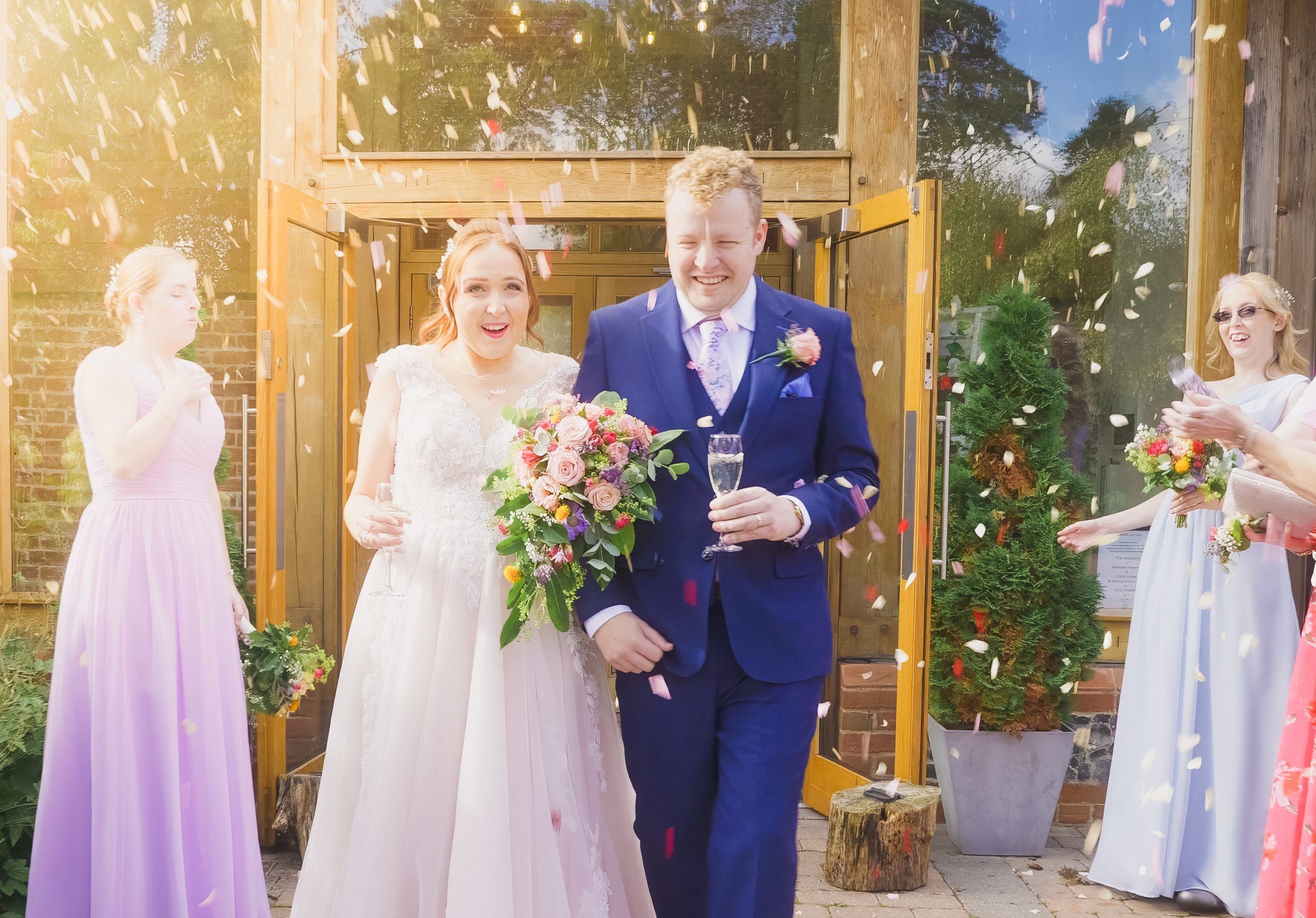 How to Create a Shot List for Your Wedding Video - bride & groom confetti thrown over them groom holding a glass and bride holding flowers